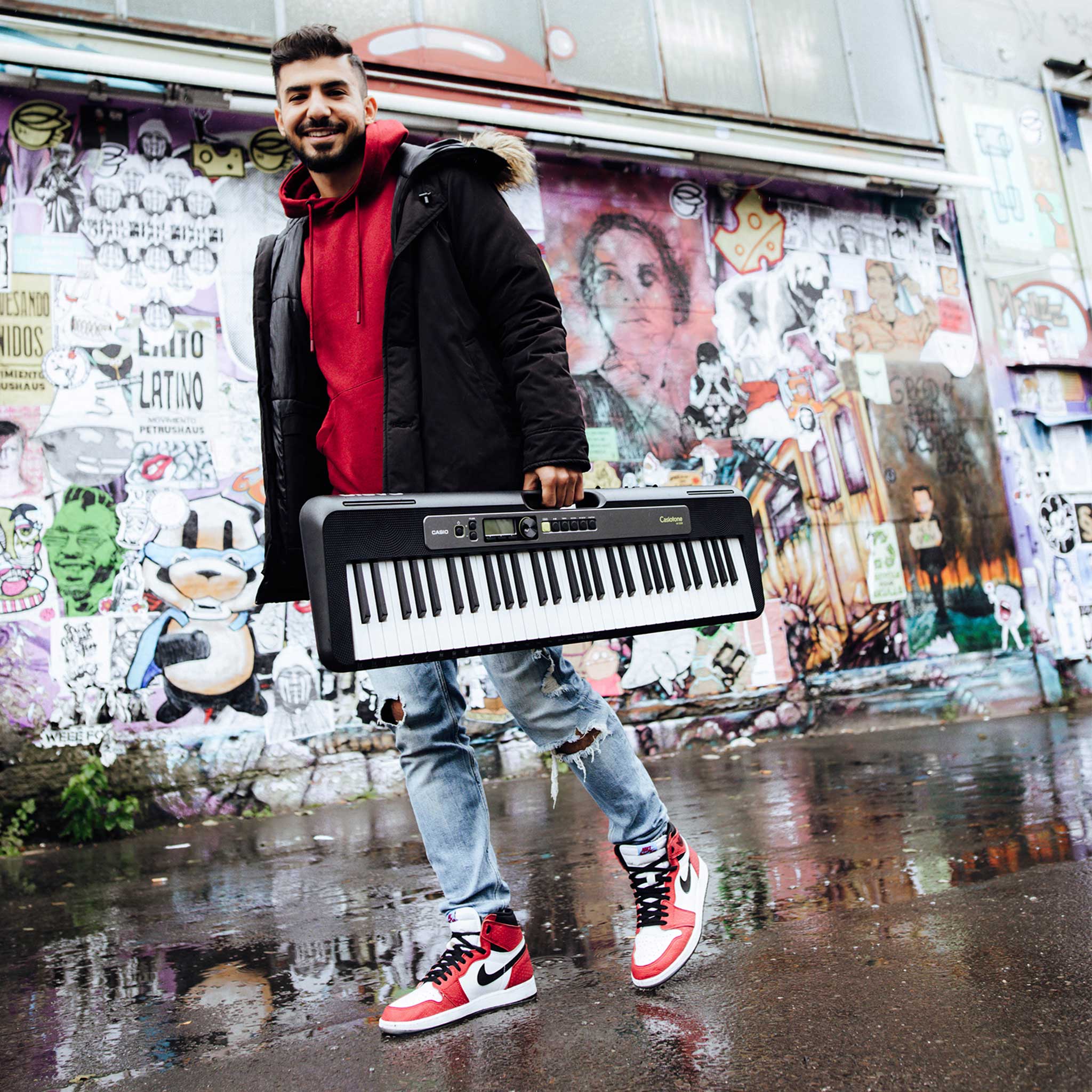Mensch mit Casio Leuchttastenkeyboard vor Graffitty Wand