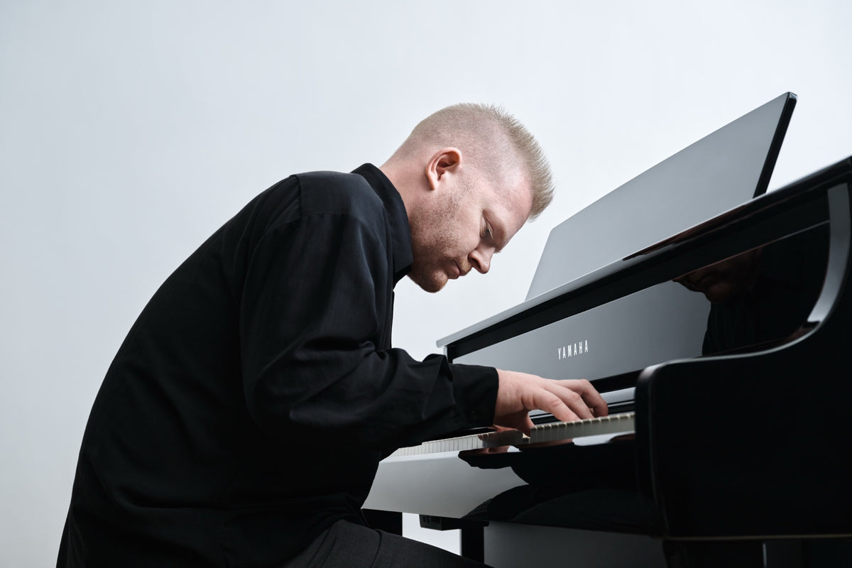 Mann spielt an einem Yamaha Clavinova CLP-875 in Schwarz poliert