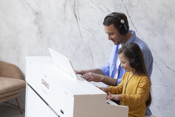 Casio Celviano AP-470 Digitalpiano Vater spielt zusammen mit Tochter mit Kopfhören Klavier