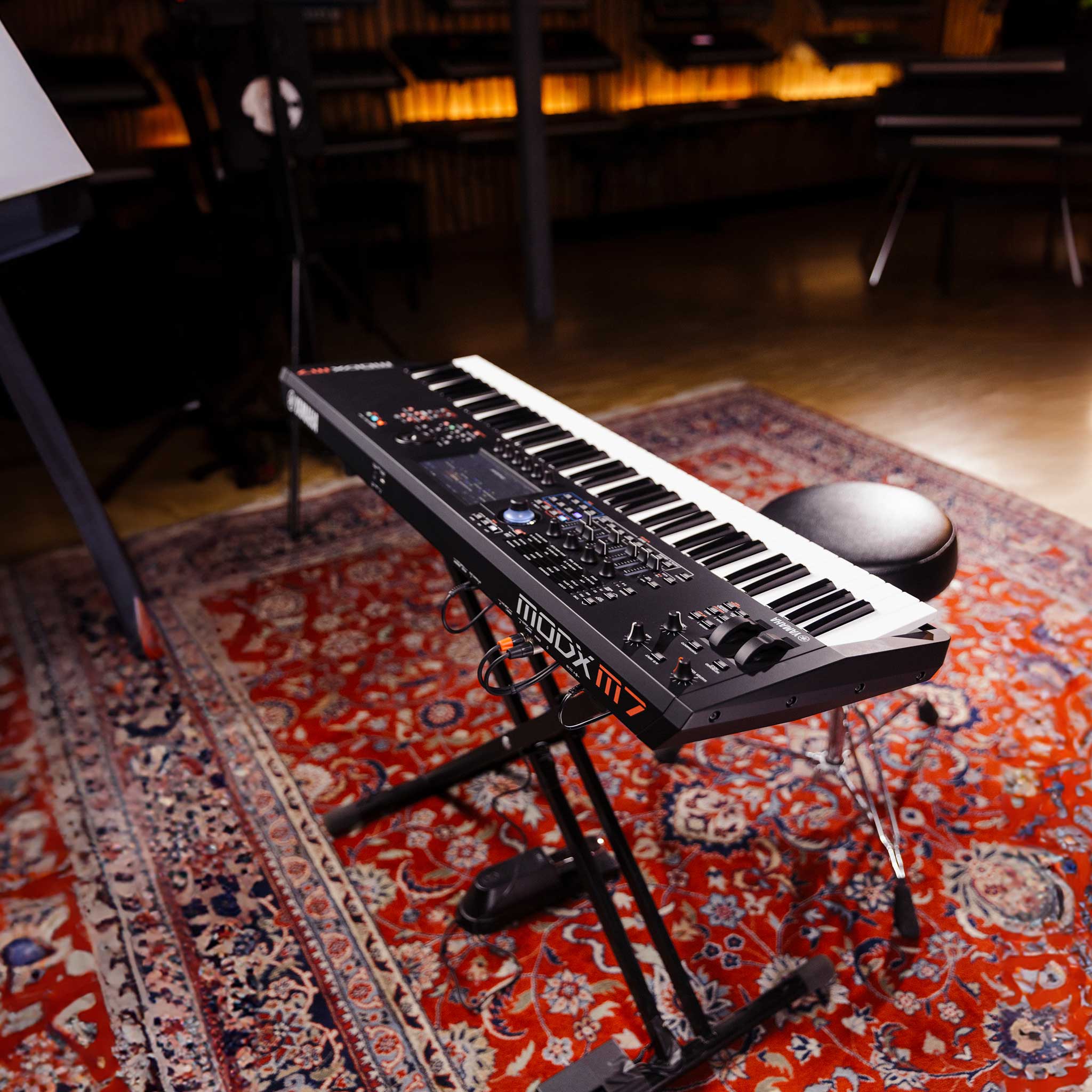 Yamaha ModX M7 auf X Ständer in einem Studio mit Klavierhocker und Teppich