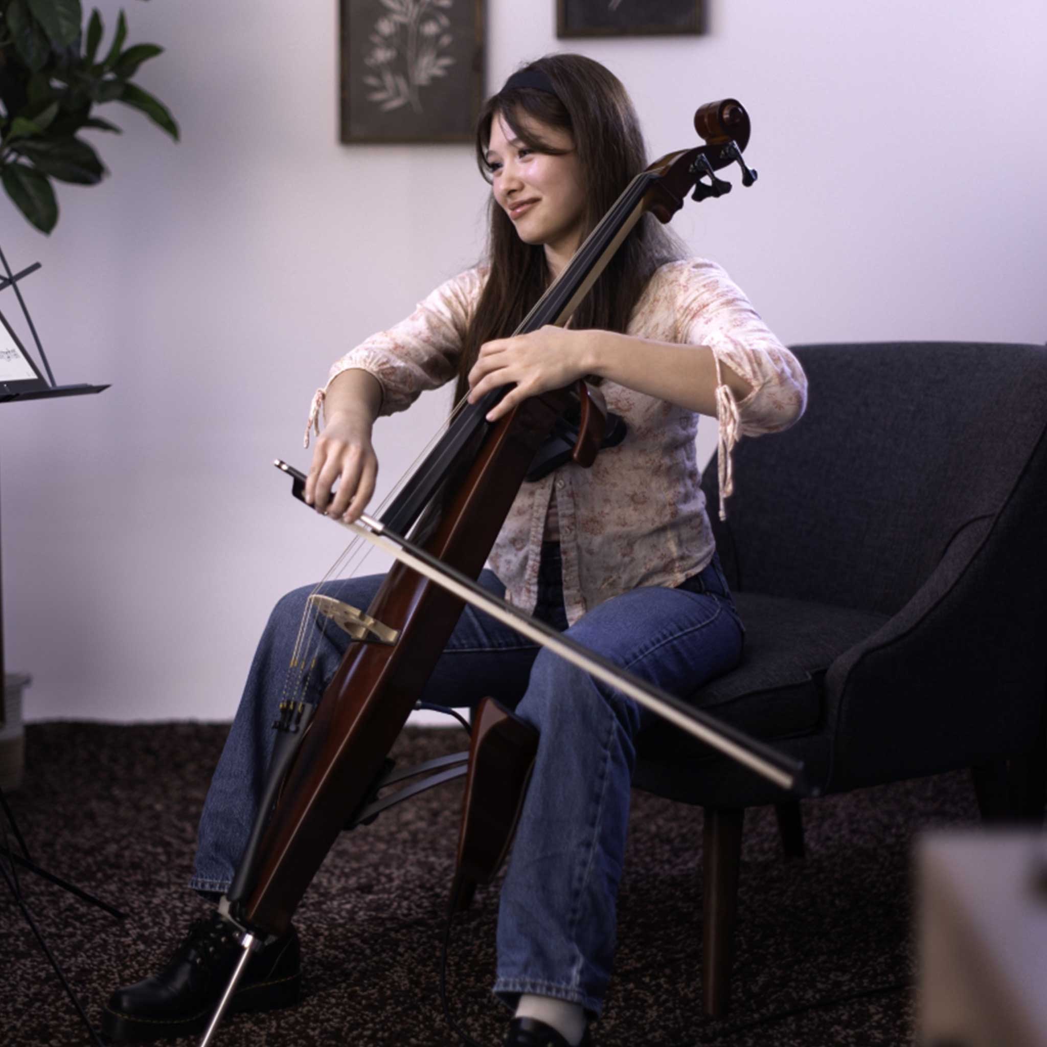 Frau spielt Yamaha Silent Cello SVC300C sitzend. Sie lächelt