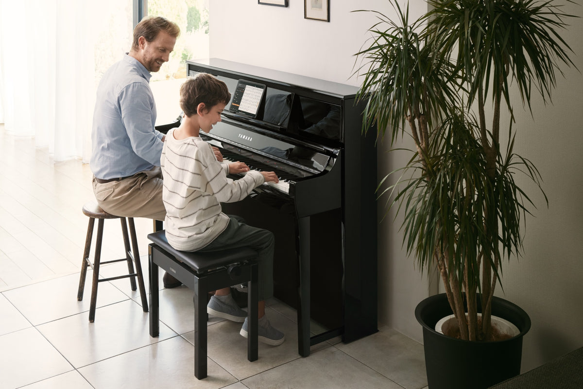 Erwachsener und Kind spielen gemeinsam an einem Yamaha Clavinova CSP-295